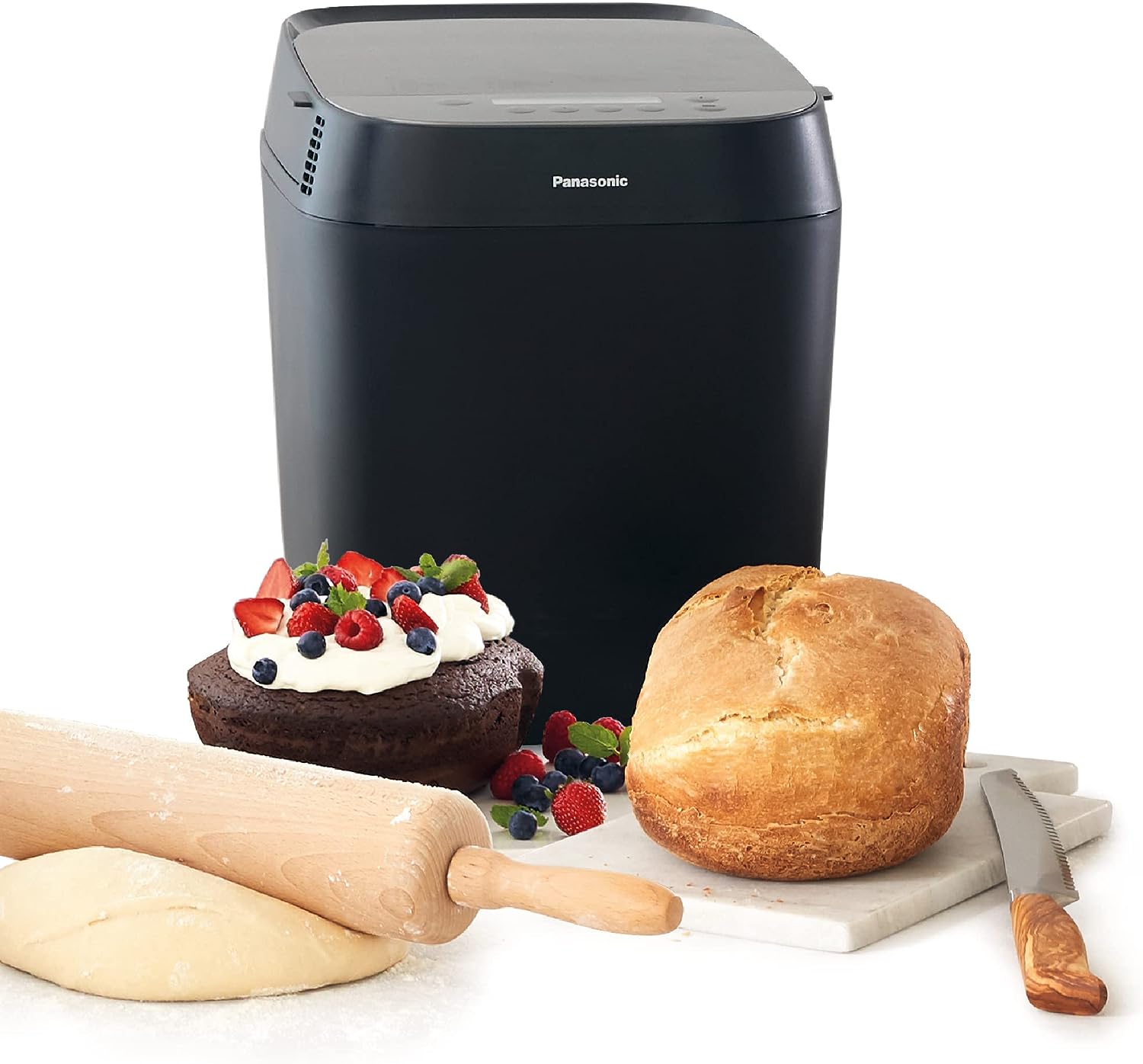 Panasonic Croustina SD-ZD2010KXH posée sur le plan de travail d'une cuisine claire, à côté d'une miche ronde, d'un pot de confiture et d'un bol de noix