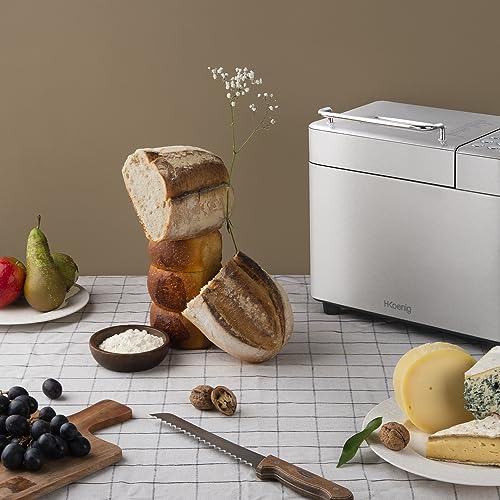 H.Koenig BAKE440 posée sur une table, entourée de pains tranchés, d'une brioche, de fromages, de raisin et d'un couteau à pain