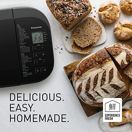 Bandeau de la Panasonic SD-YR2540 avec les 32 programmes classés en Bread, Gluten Free, Dough, Sweet et Manual, à côté d'une miche au levain grignée et de petits pains